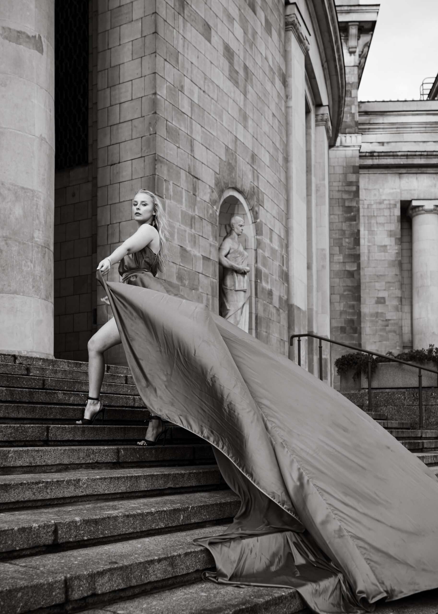 Piękna kobieta, pozuje w długiej sukni flyingdress na tle miasta, sesja zdjęciowa w Warszawie, Weddatelier Michał Dubicki Fotografia