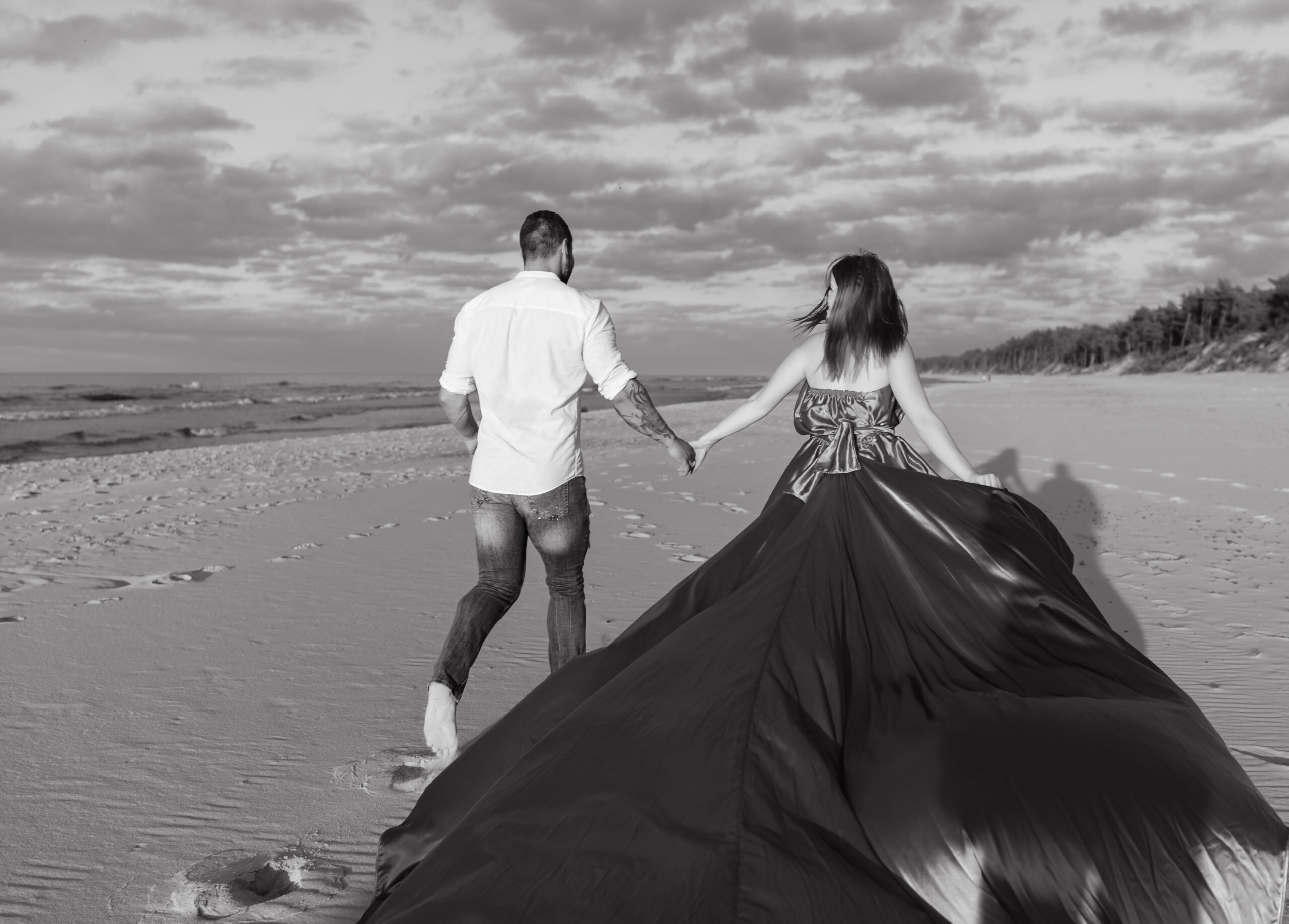 Para zakochanych biegnie wzdłuż plaży podczas narzeczeńskiej sesji zdjęciowej nad morzem, WeddAtelier Fotograf Warszawa Michał Dubicki