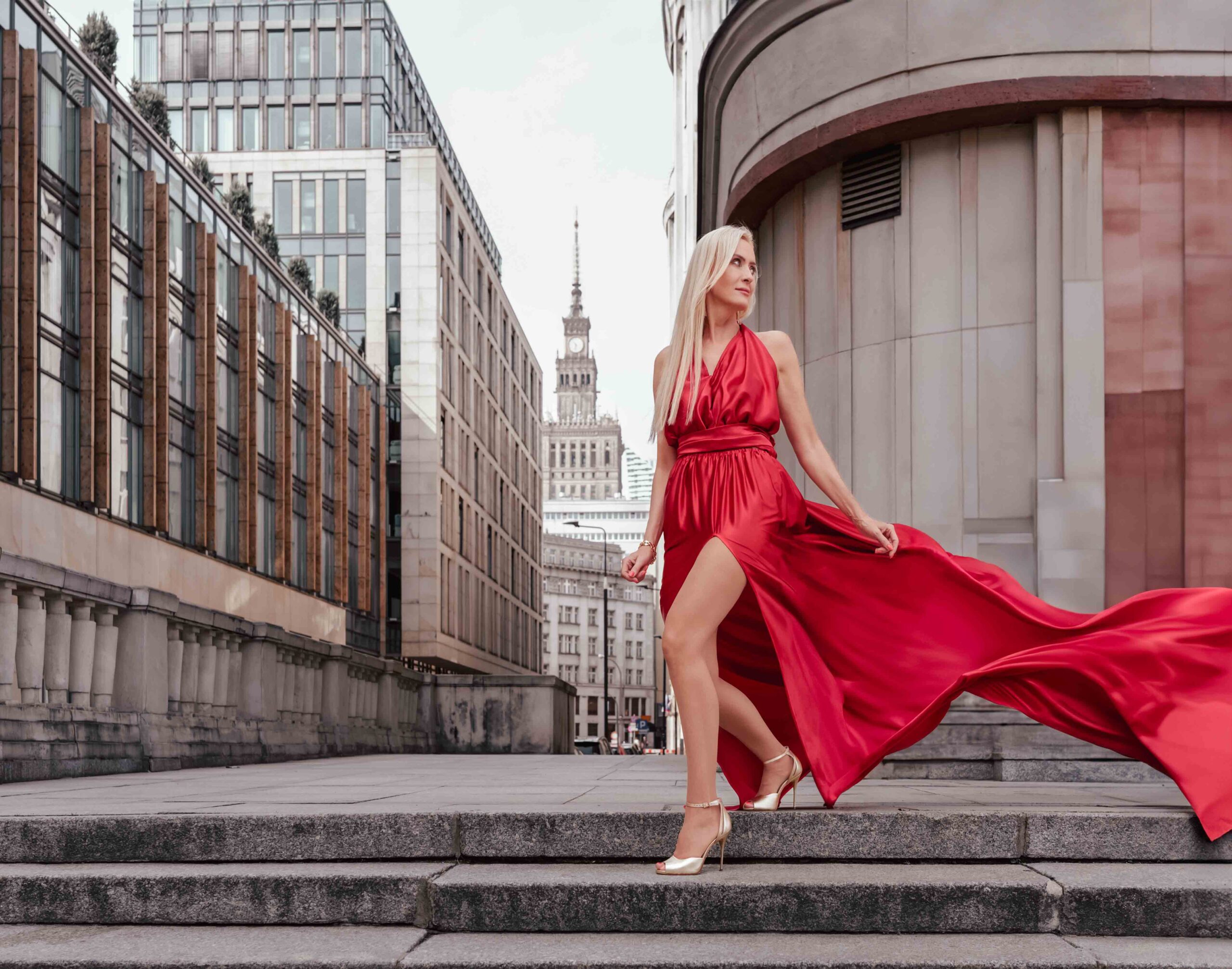 Sesja zdjęciowa w Warszawie, modelka w długiej czerwonej sukni, w tle Pałac Kultury i Nauki, Fotograf Ślubny Warszawa WeddAtelier.pl Fotografia i Film Ślubny Michał Dubicki