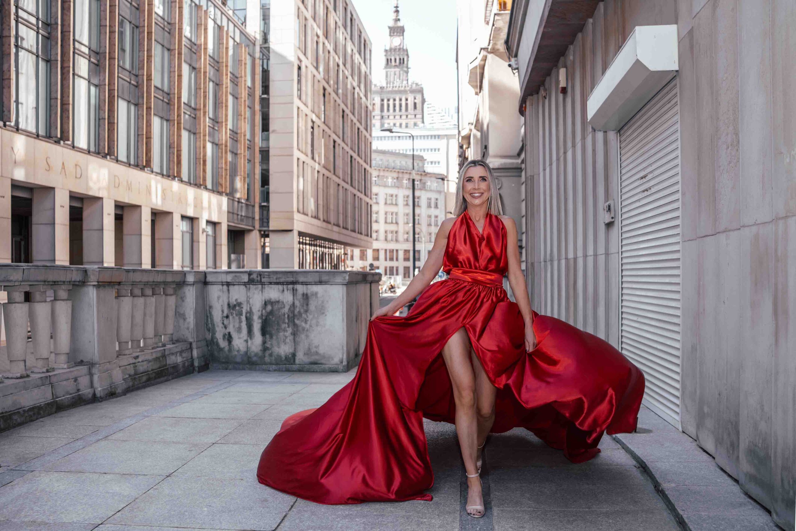 Sesja zdjęciowa w sukniach Flying Dress w Warszawie, modelka w długiej czerwonej sukni, w tle Pałac Kultury i Nauki Fotograf Ślubny Warszawa WeddAtelier.pl Fotografia i Film Ślubny