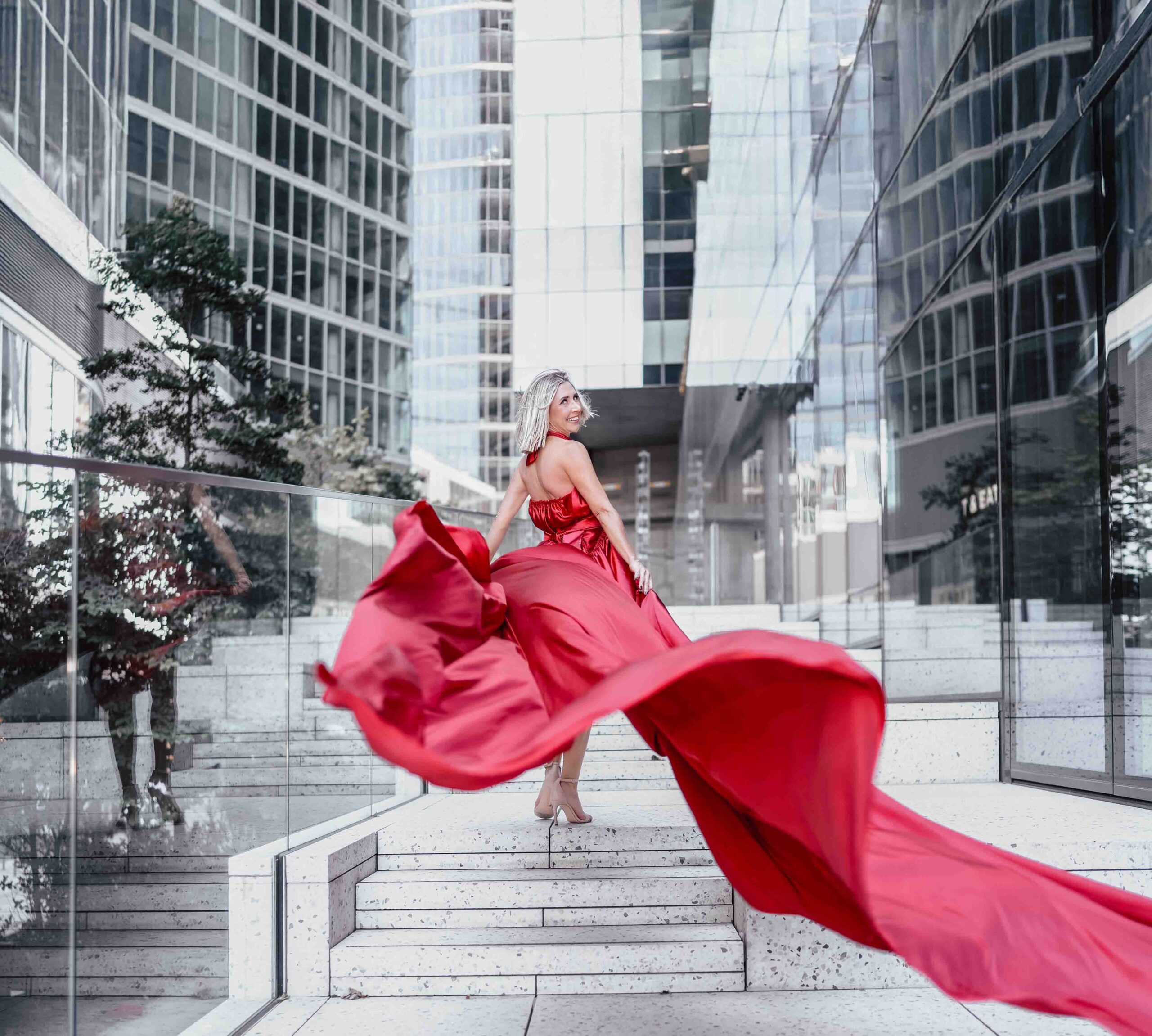 Sesja zdjęciowa w sukni Flyingdress w Warszawie, modelka w długiej czerwonej sukni na tle wieżowców, Fotograf Ślubny Warszawa WeddAtelier.pl Fotografia i Film Ślubny