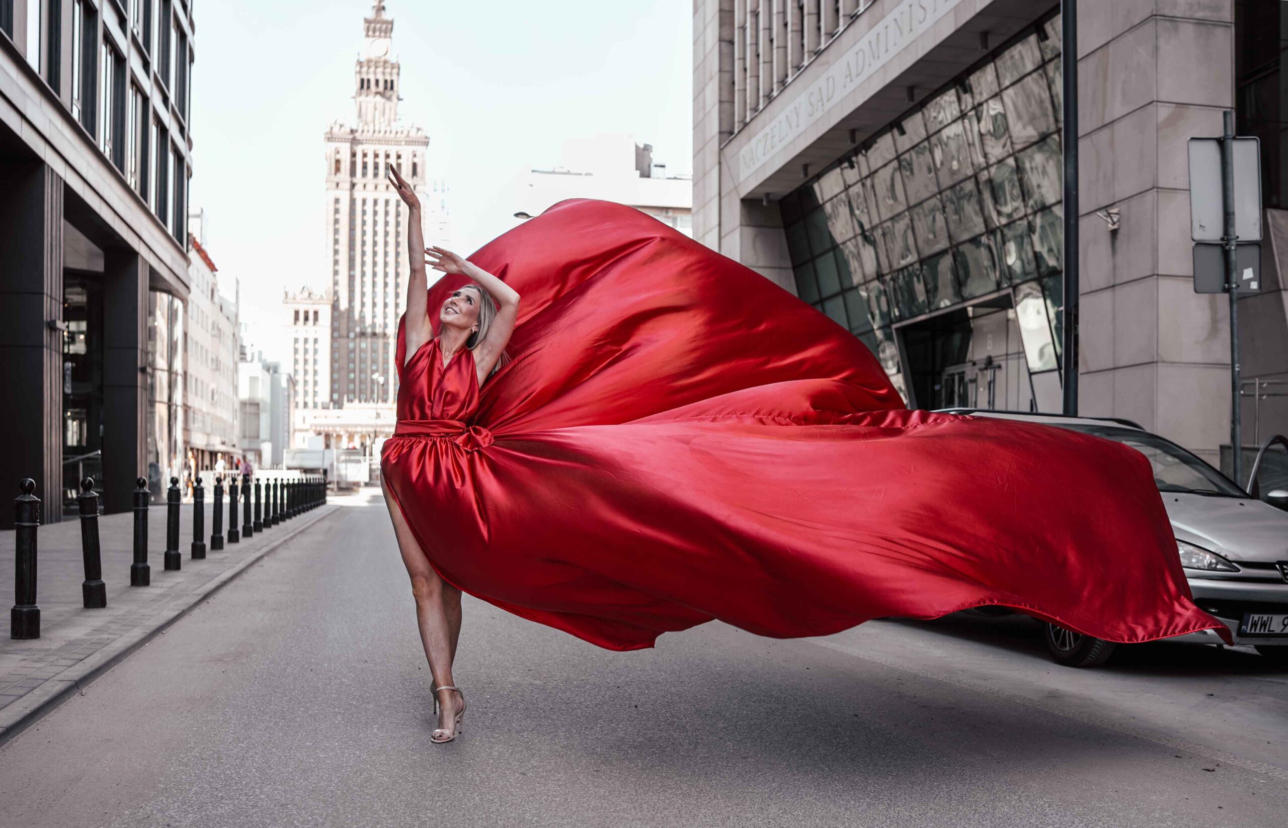 Sesja zdjęciowa w sukniach Flying Dress w Warszawie, modelka w długiej czerwonej sukni, w tle Pałac Kultury i Nauki Fotograf Ślubny Warszawa WeddAtelier.pl Fotografia i Film Ślubny