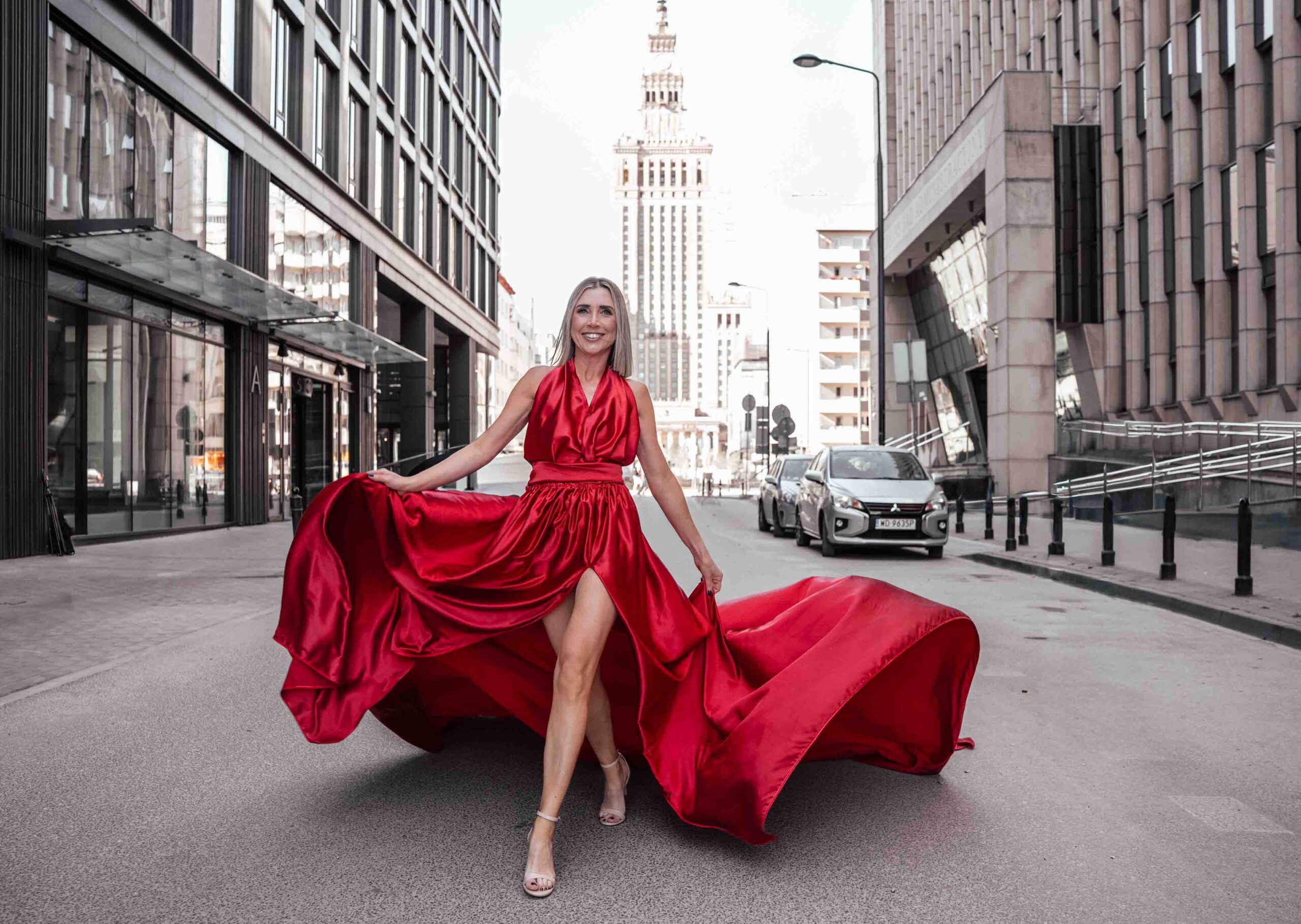 Sesja zdjęciowa w sukniach Flying Dress w Warszawie, modelka w długiej czerwonej sukni, w tle Pałac Kultury i Nauki Fotograf Ślubny Warszawa WeddAtelier.pl Fotografia i Film Ślubny